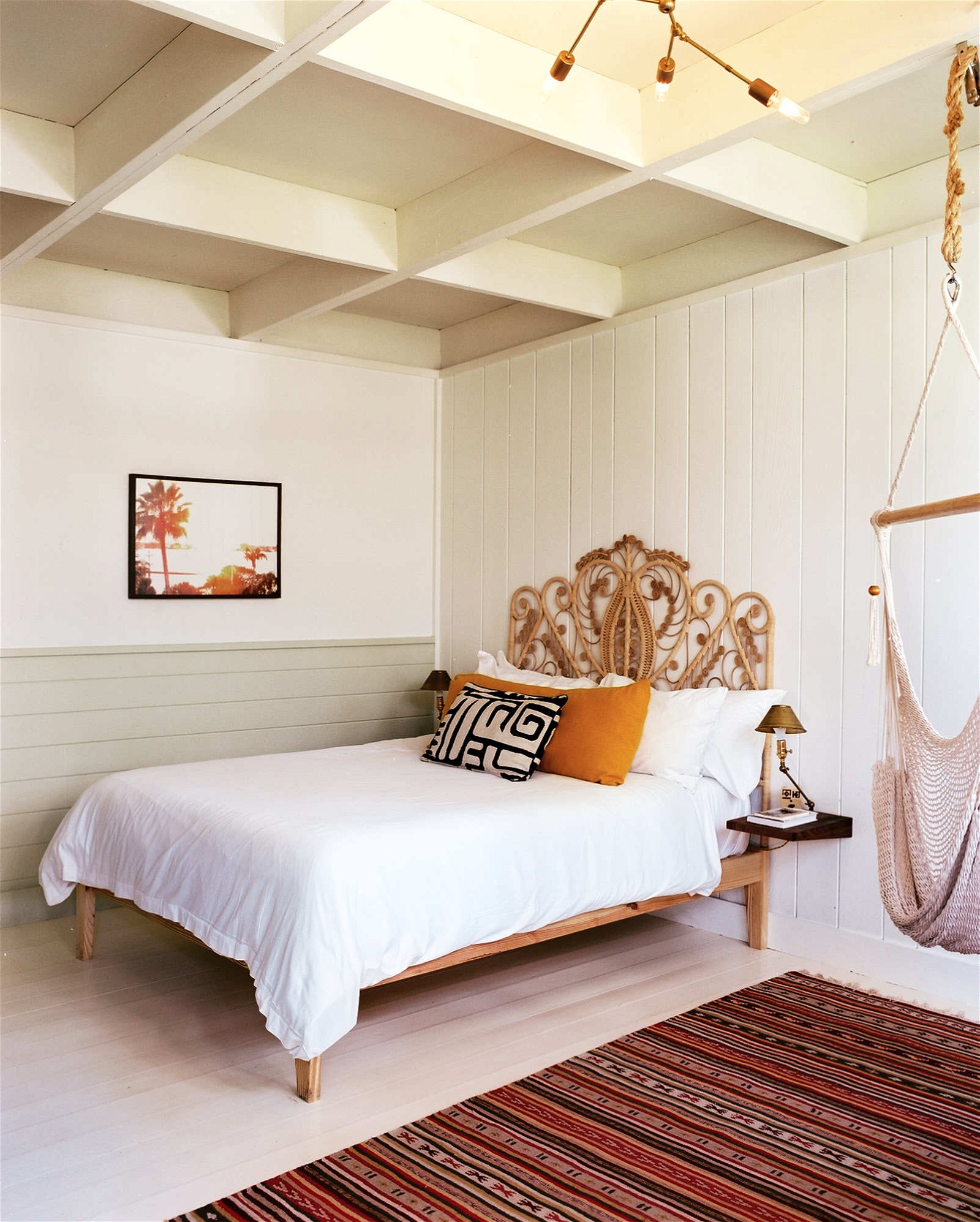White minimalist bedroom with orange accents and hammock chair