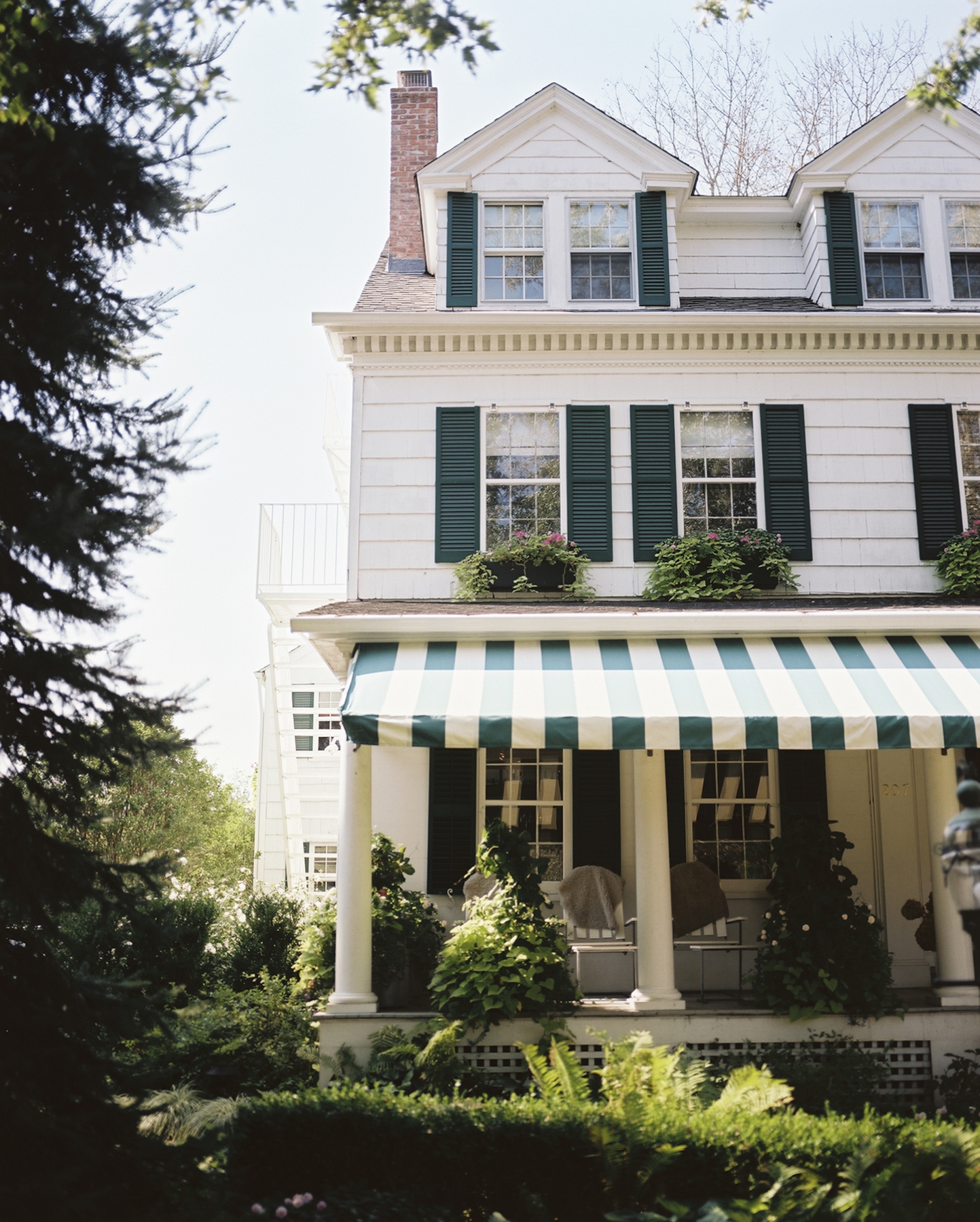 The Maidstone Hotel in East Hampton NY with green shutters and striped awning
