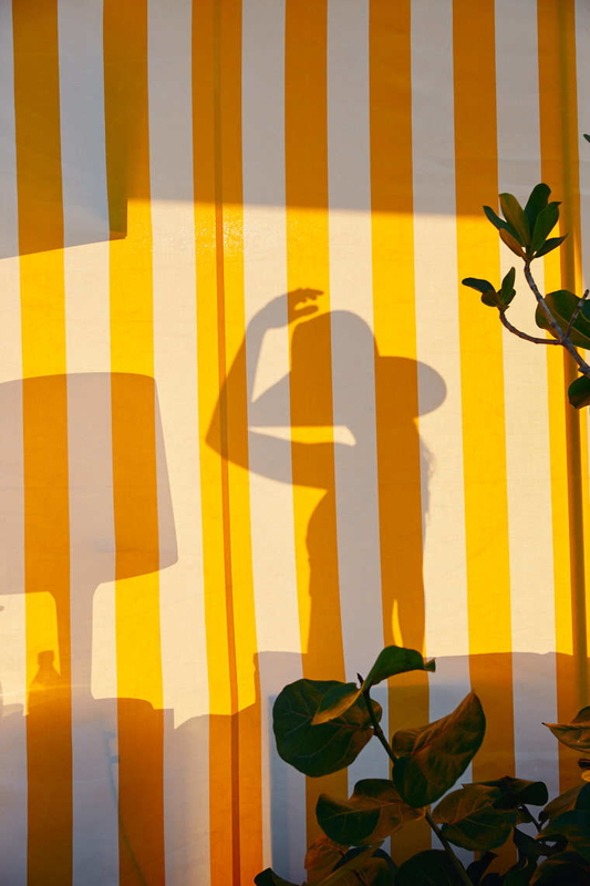 Hospitality photography of woman's silhouette on yellow striped wall