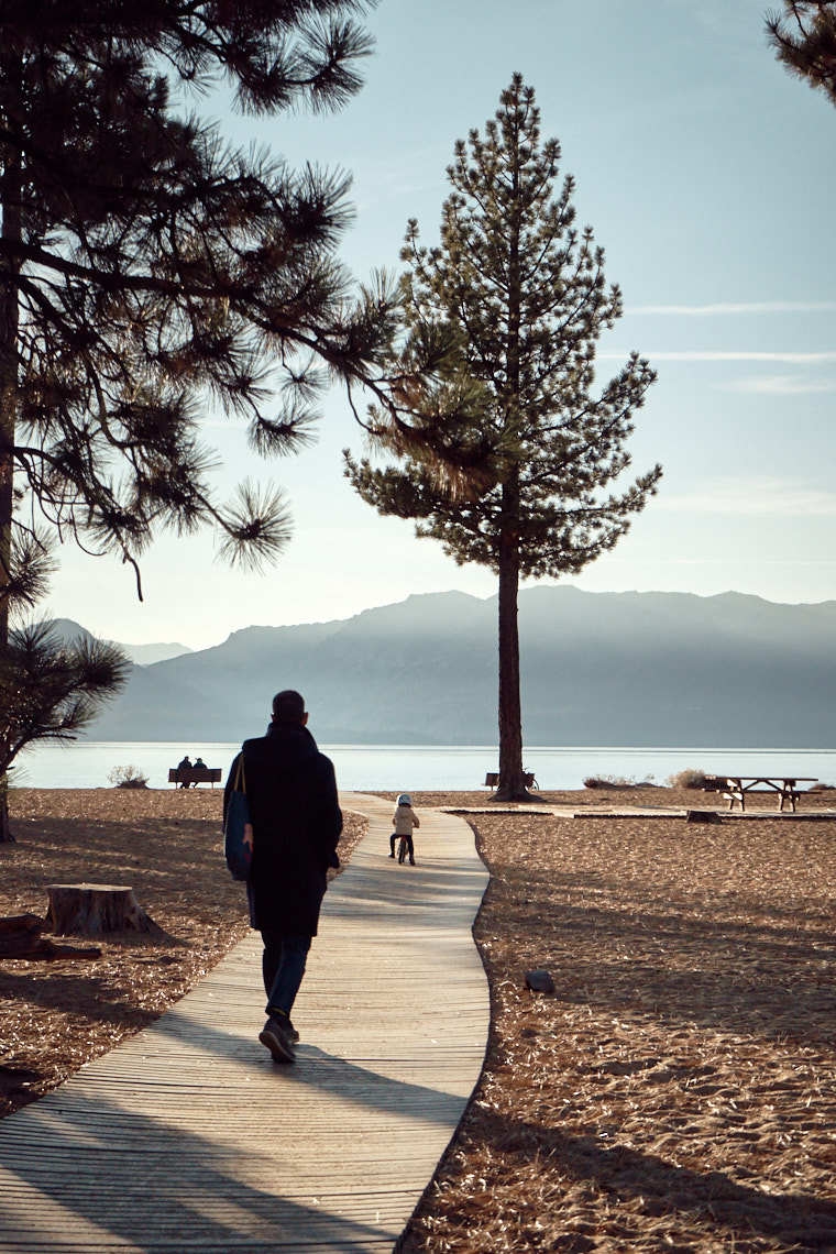 Man walks down boardwalk in Tahoe following child on a bike