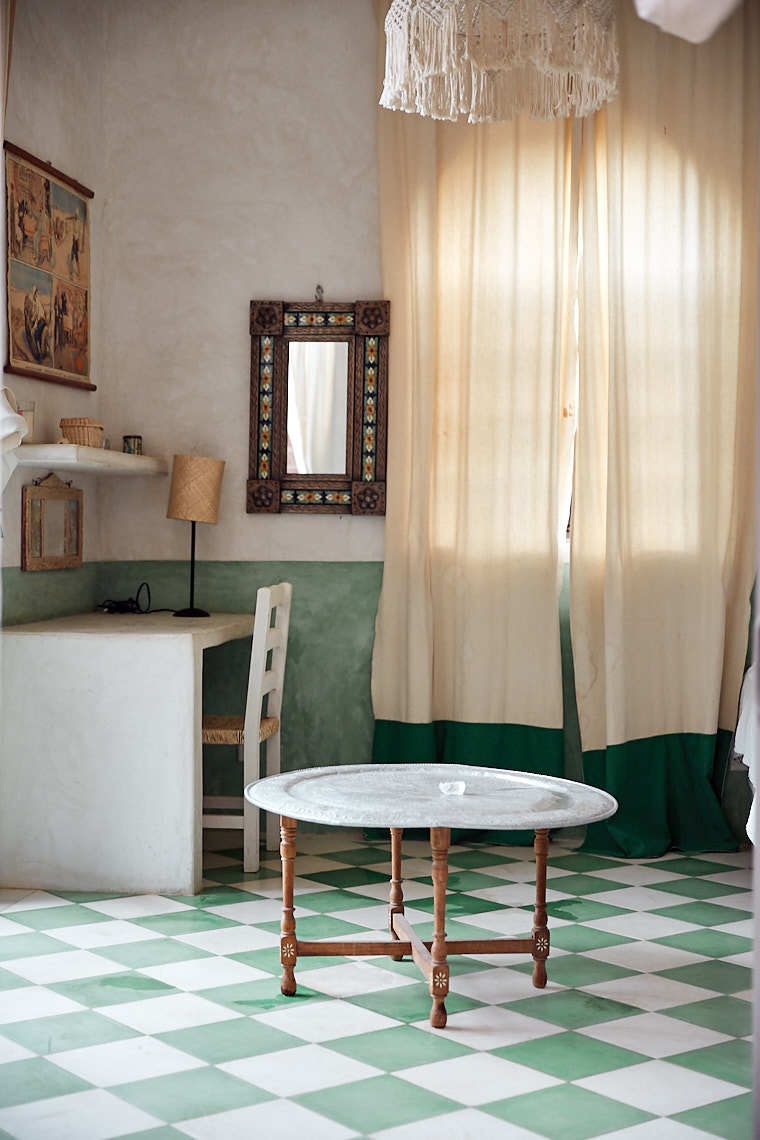 Small wooden table with green and white checkerboard tile floor and macrame lamp shade