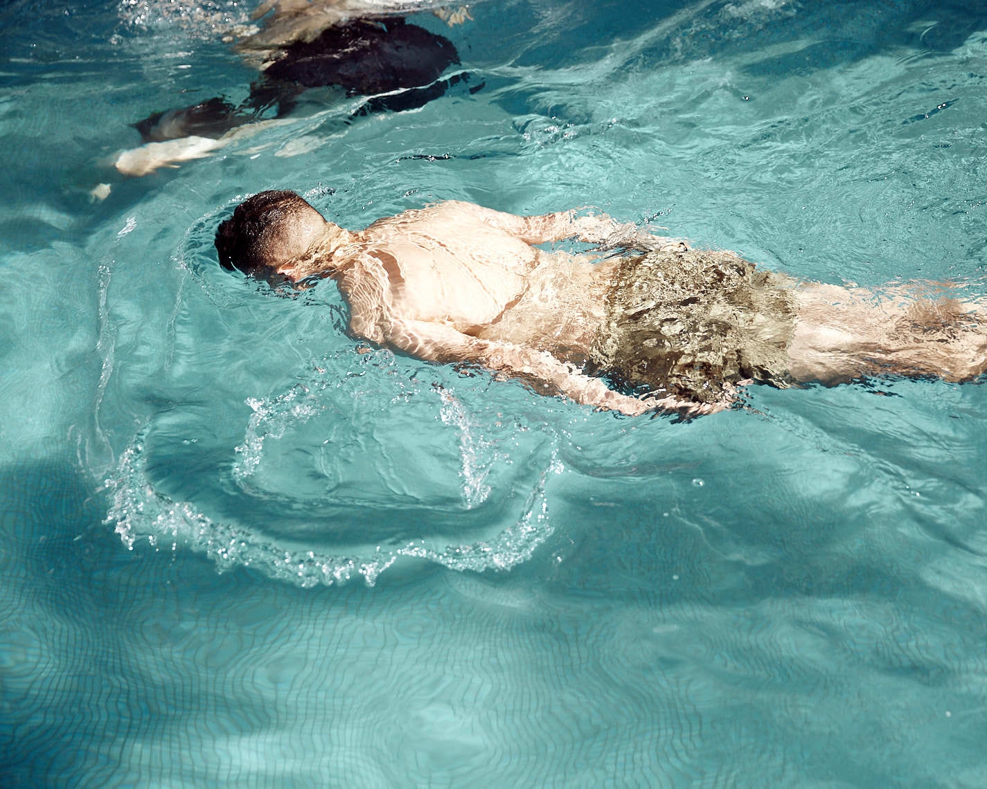 Boy in green trunks swimming in pool