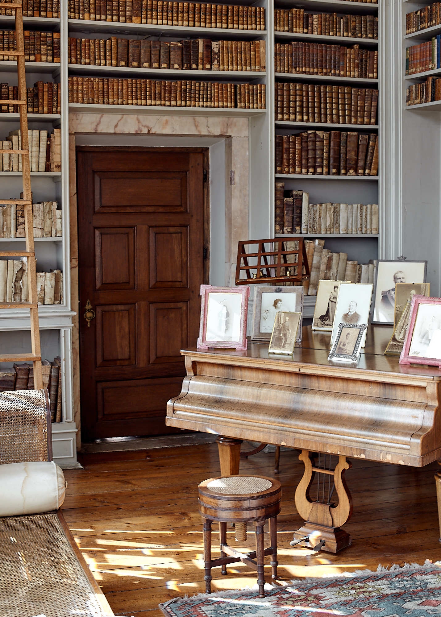 Shelves of antique books and photographs on grand piano