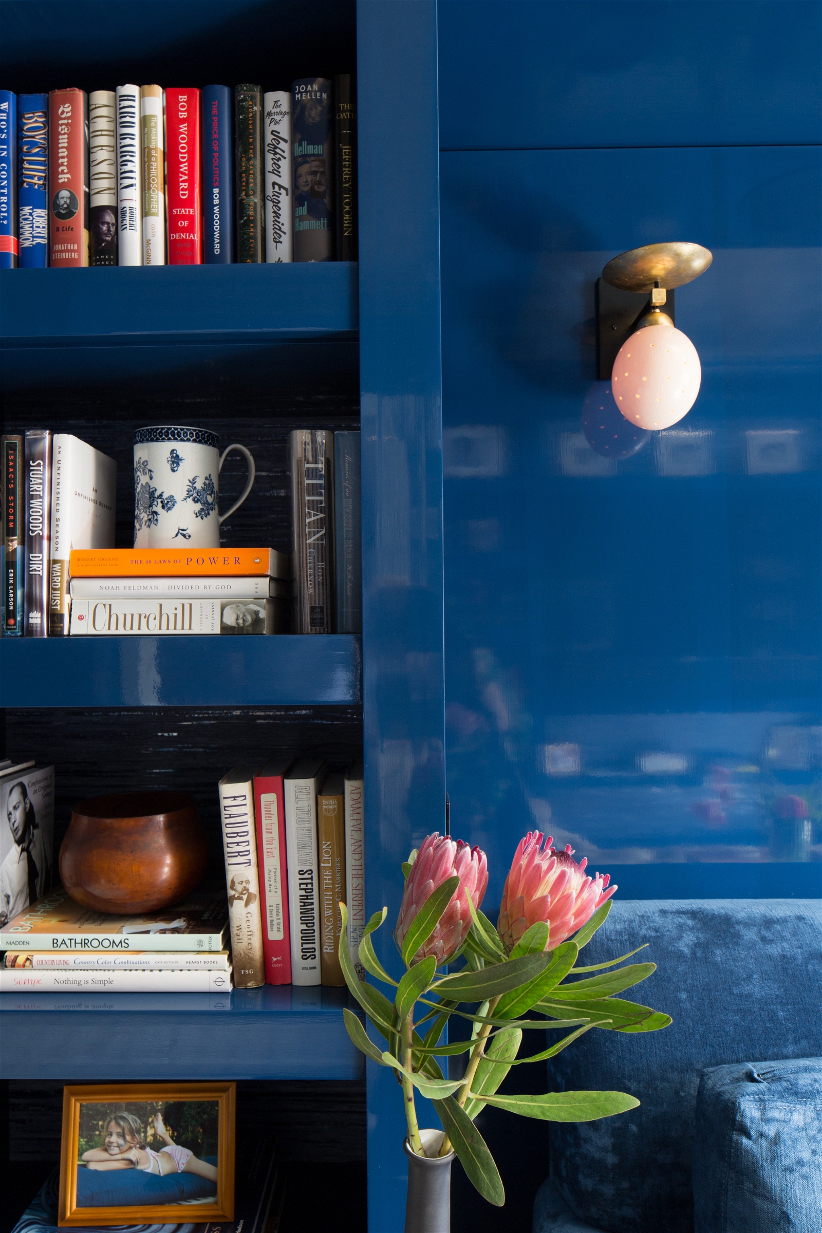 Royal blue bedroom with built-in bookshelves and gold light fixtures