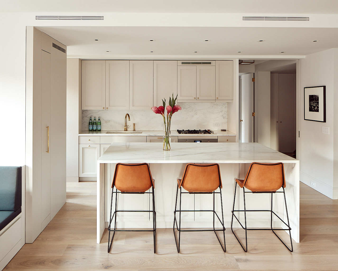 Elegant white kitchen with orange bar seats in Wettling Neuwirth