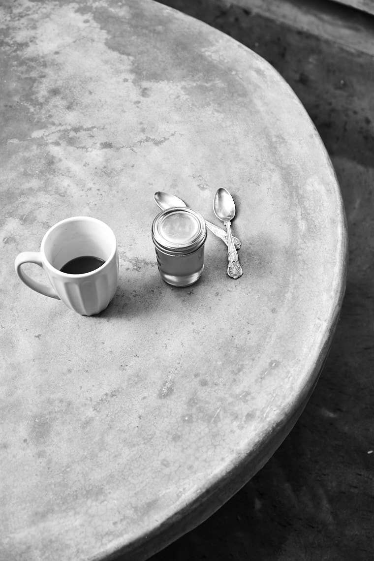Black and white photograph with cup of coffee two spoons and a mason jar