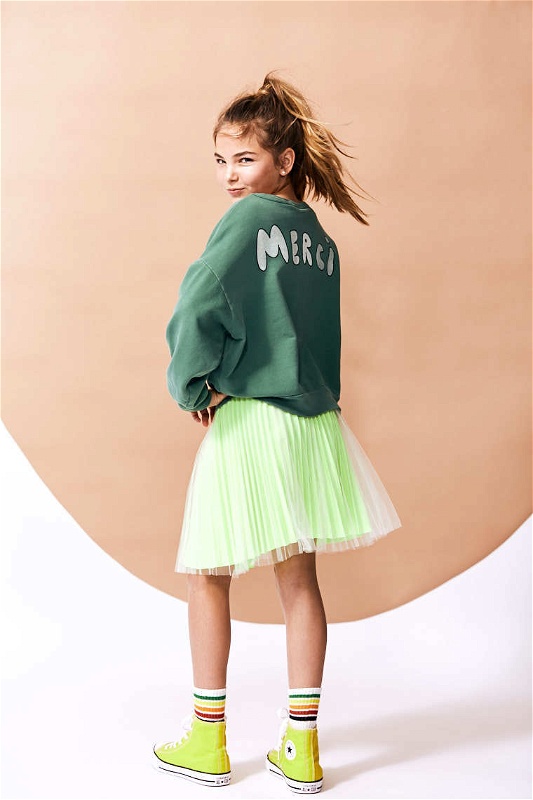 Girl in lime green tutu and converses showcases clothing line