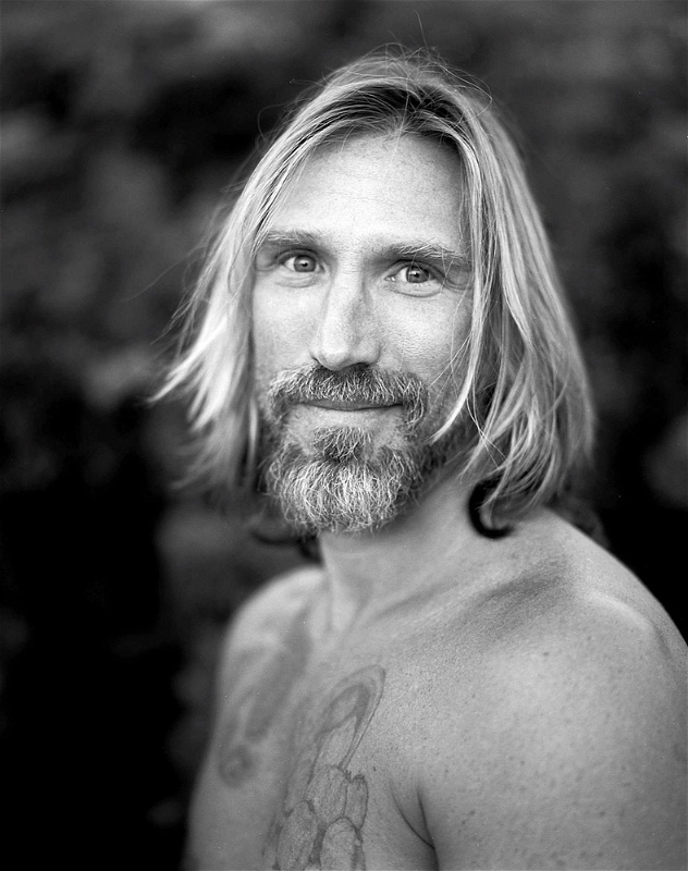 Black and white headshot of bearded man with long blonde hair