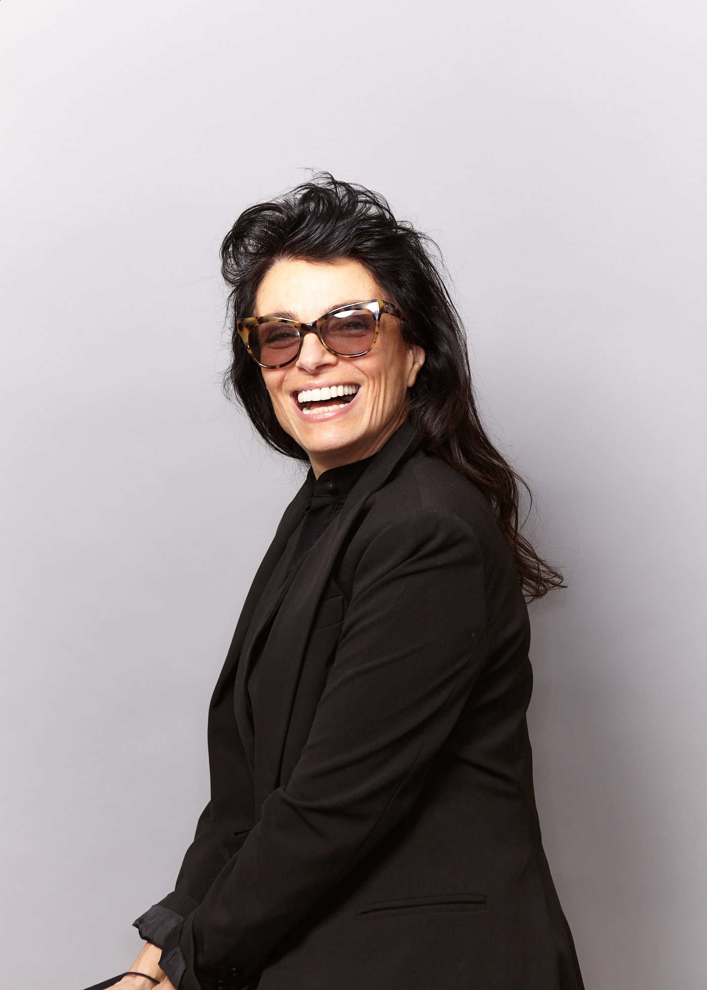 Laughing female model in black blazer and sunglasses
