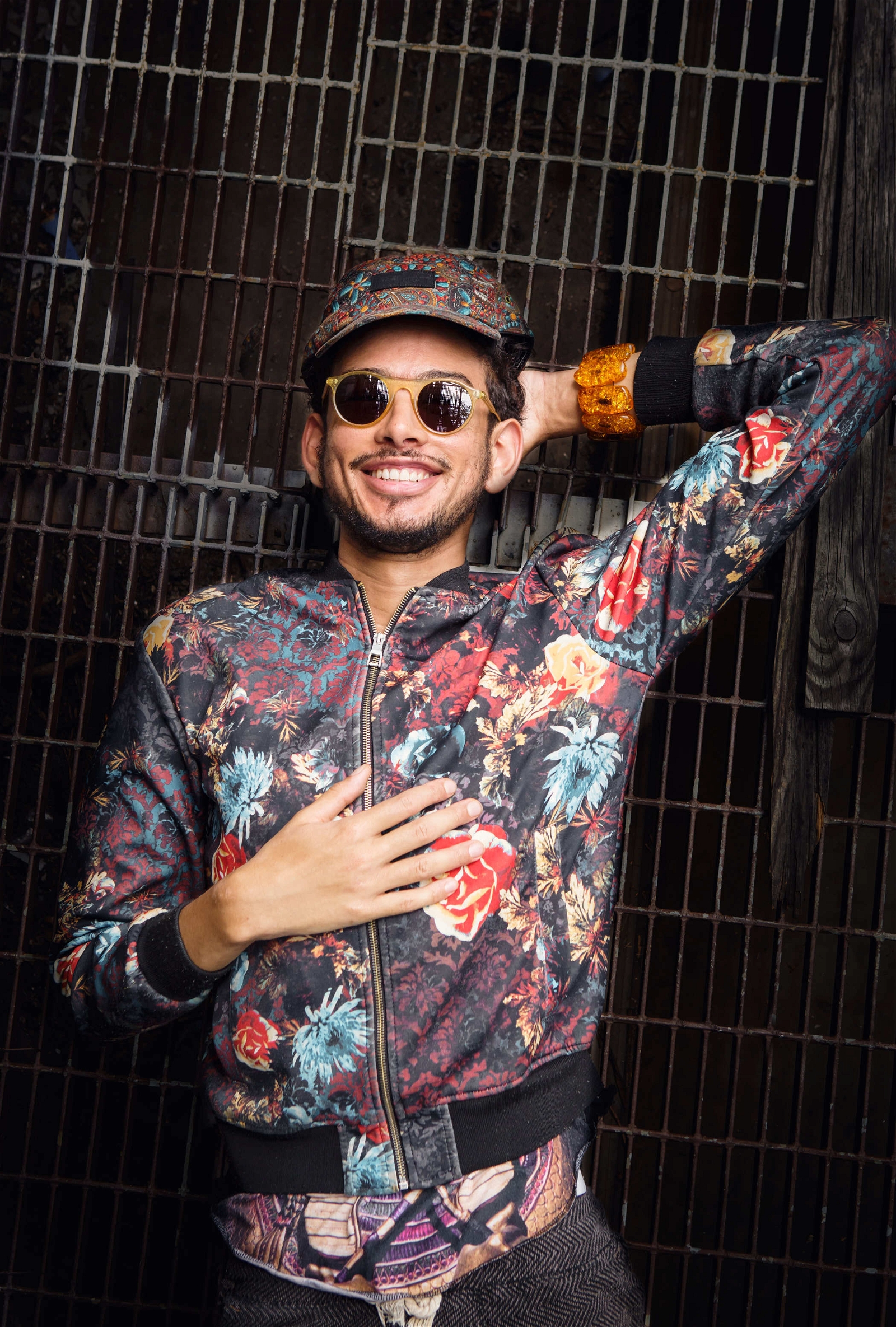 Smiling man in floral bomber jacket colorful hat and sunglasses