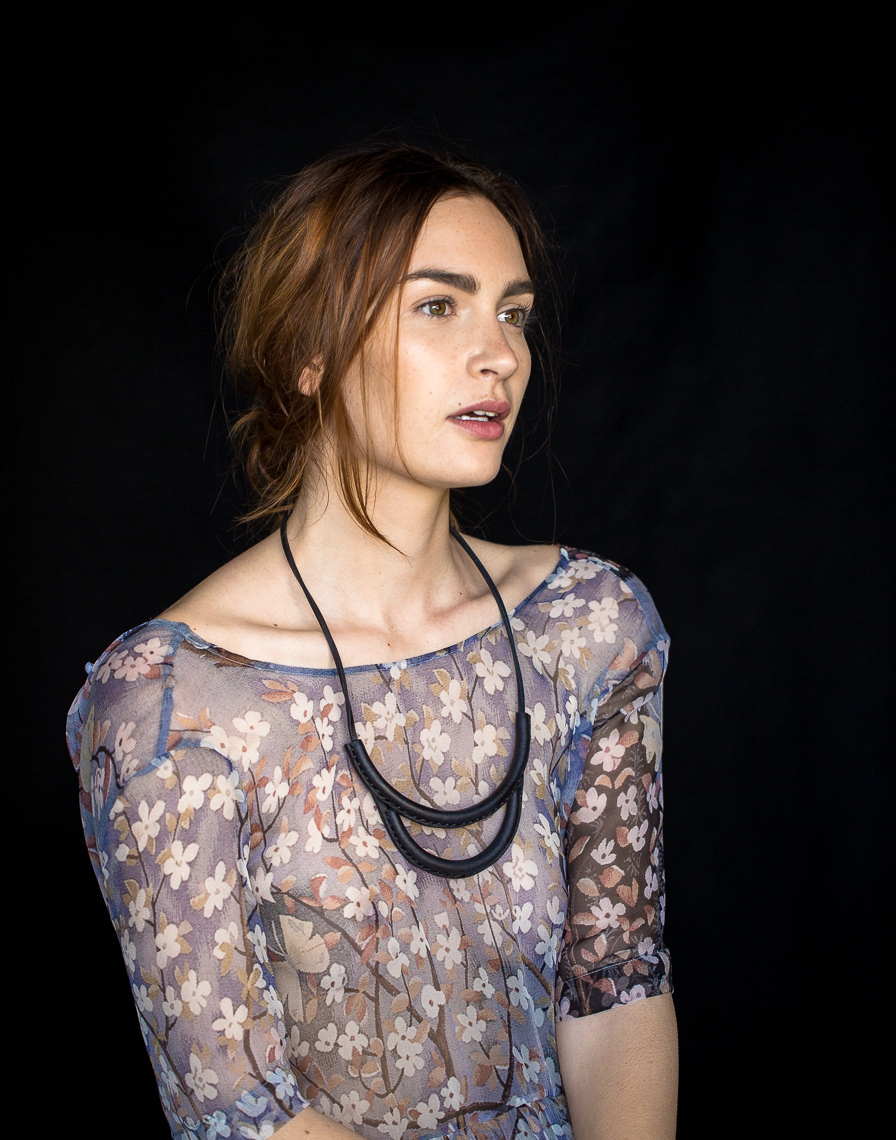 Model in sheer blue flowered blouse and black necklace
