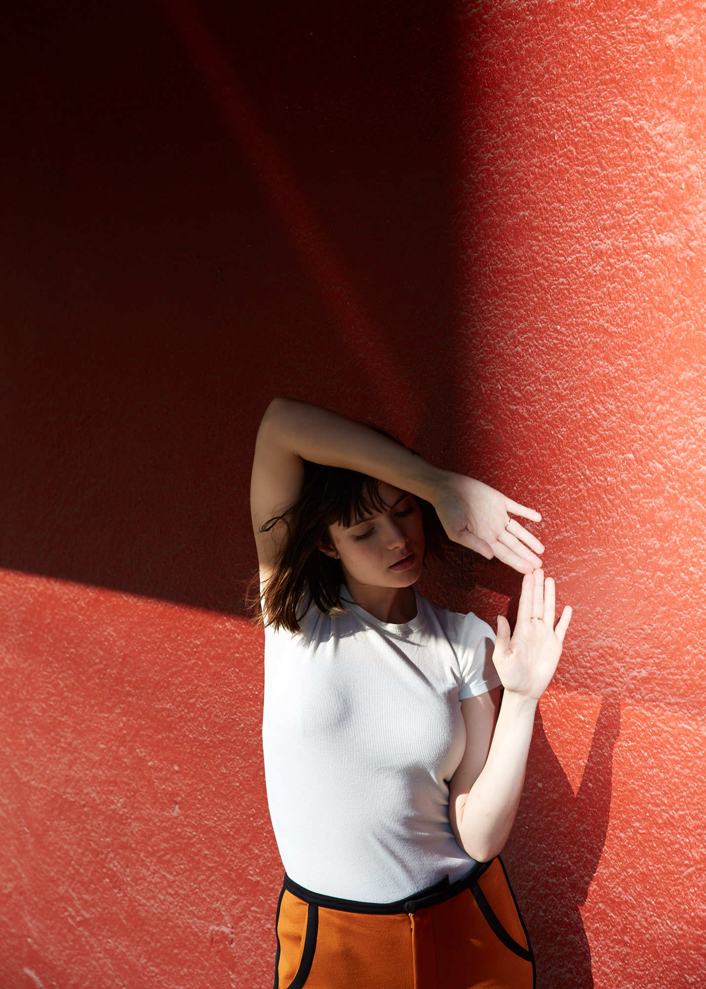 Francesca editorial portrait of girl with brown bangs against red wall