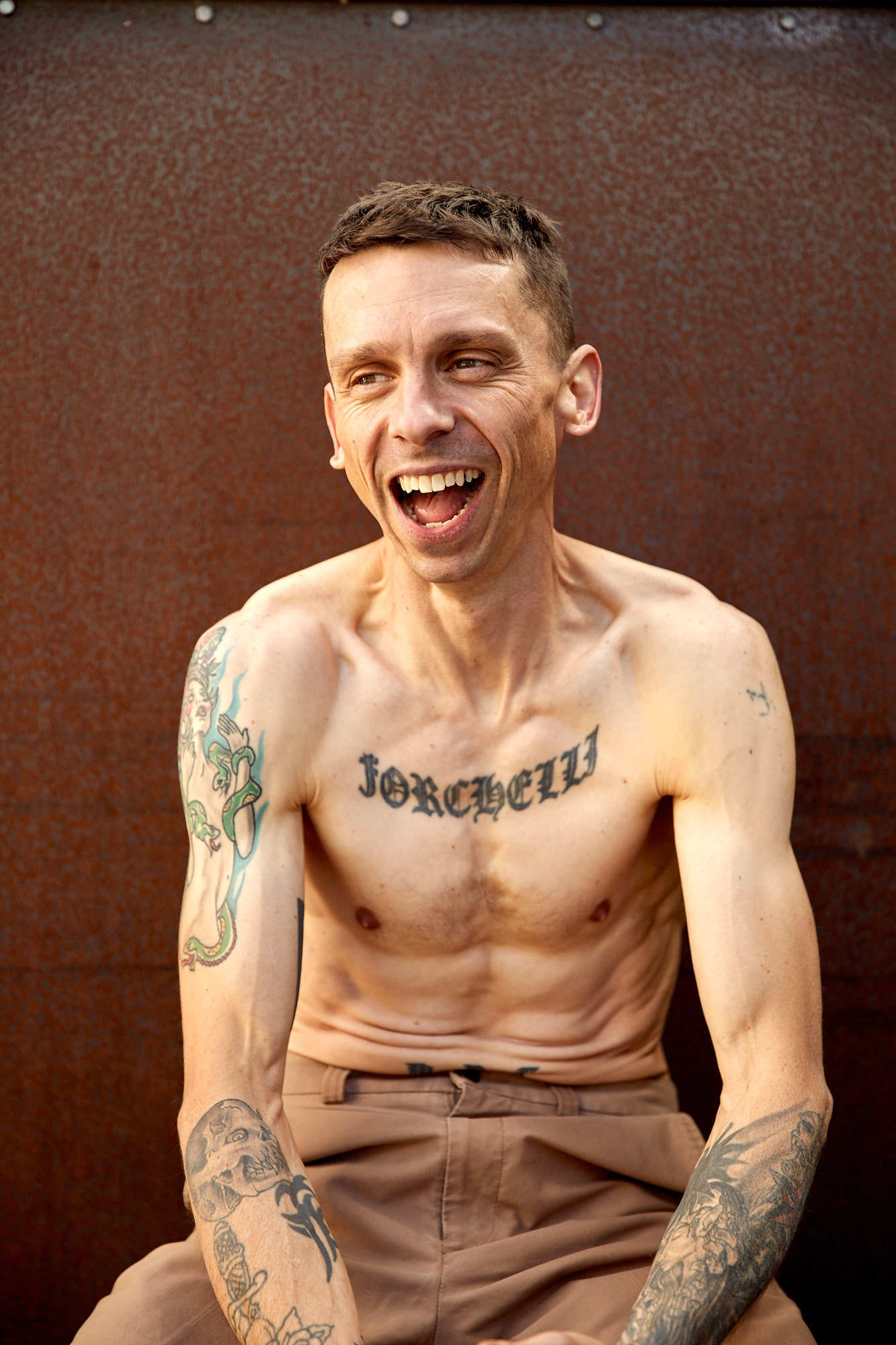 Smiling shirtless man with chest and arm tattoos