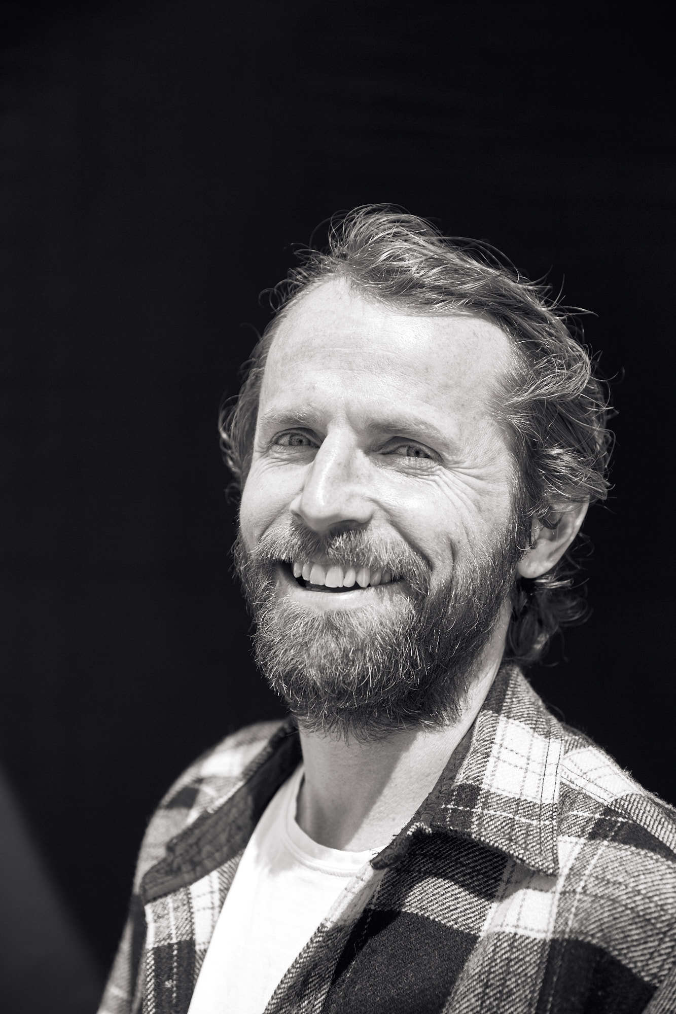 Closeup black and white portrait for West Coast Craft of smiling bearded man