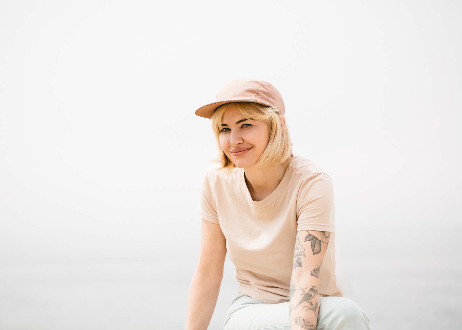 Blonde woman in pink monochromatic shirt and hat with tattoo sleeve