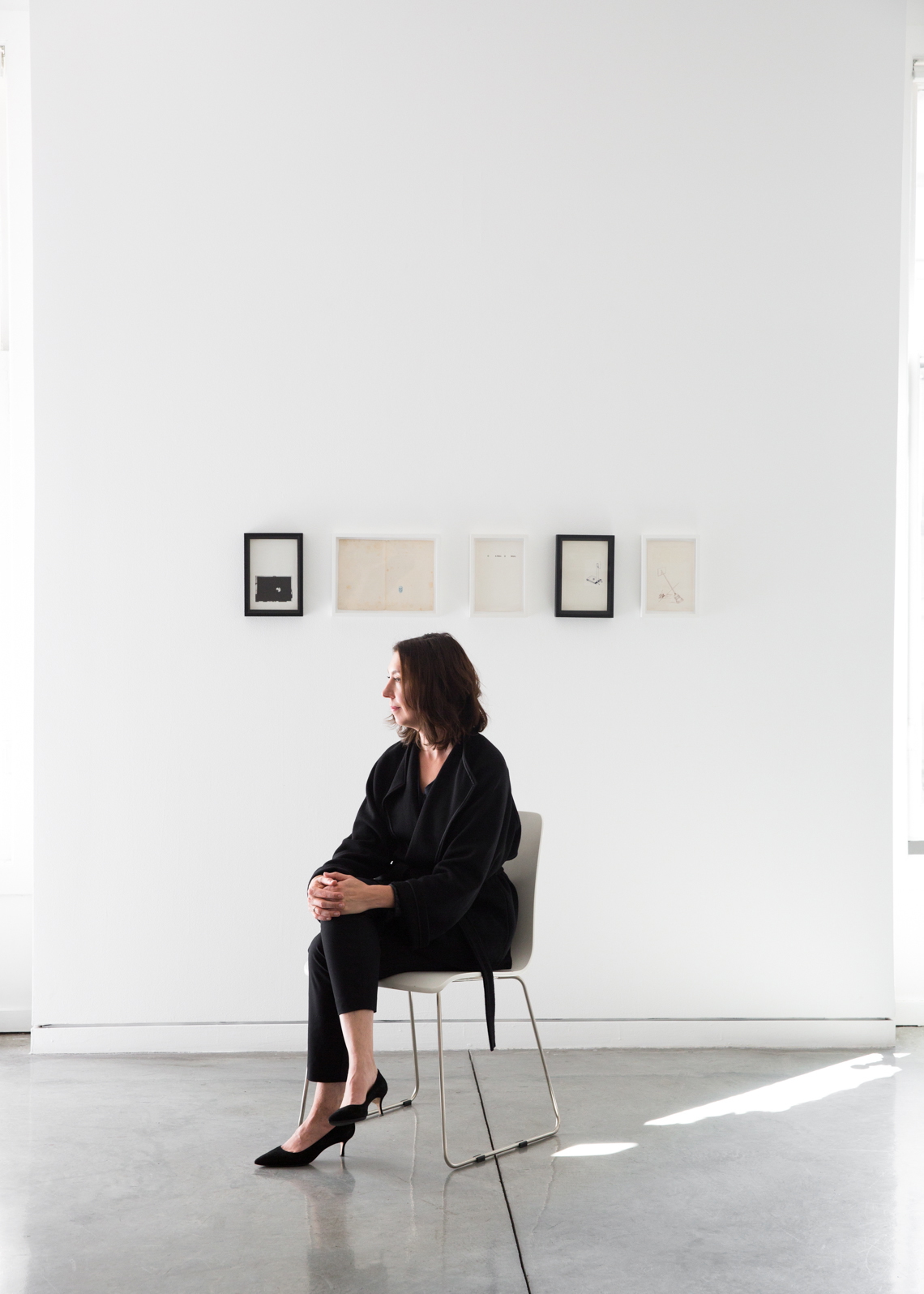 The silhouette of a woman sitting in an art gallery wearing all black