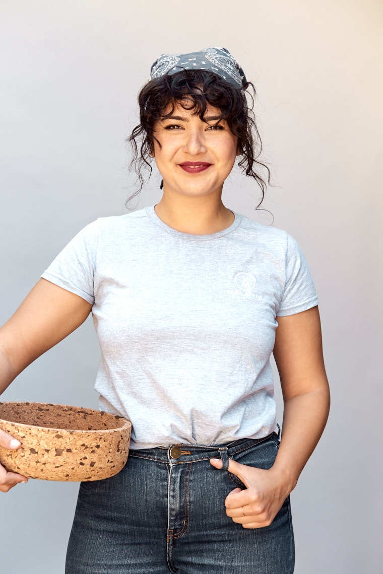 Young brunette woman in gray t-shirt handkerchief and jeans holding cork bowl