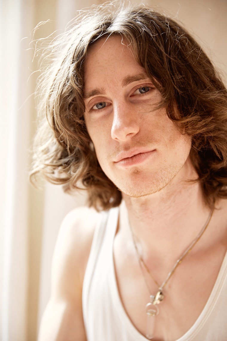 Young man with long brown curly hair blue eyes and necklace | The Morrisons  Photo