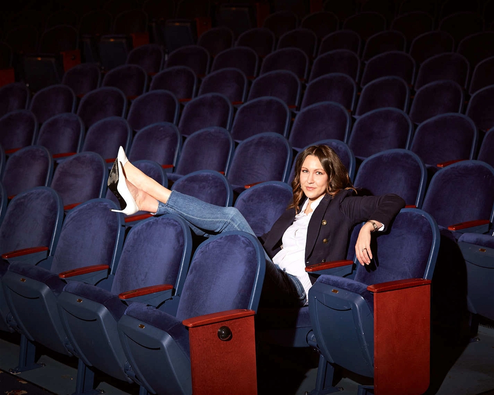 Entrepreneur Aubrey Bergauer in blue blazer sitting in theater for Performing Arts