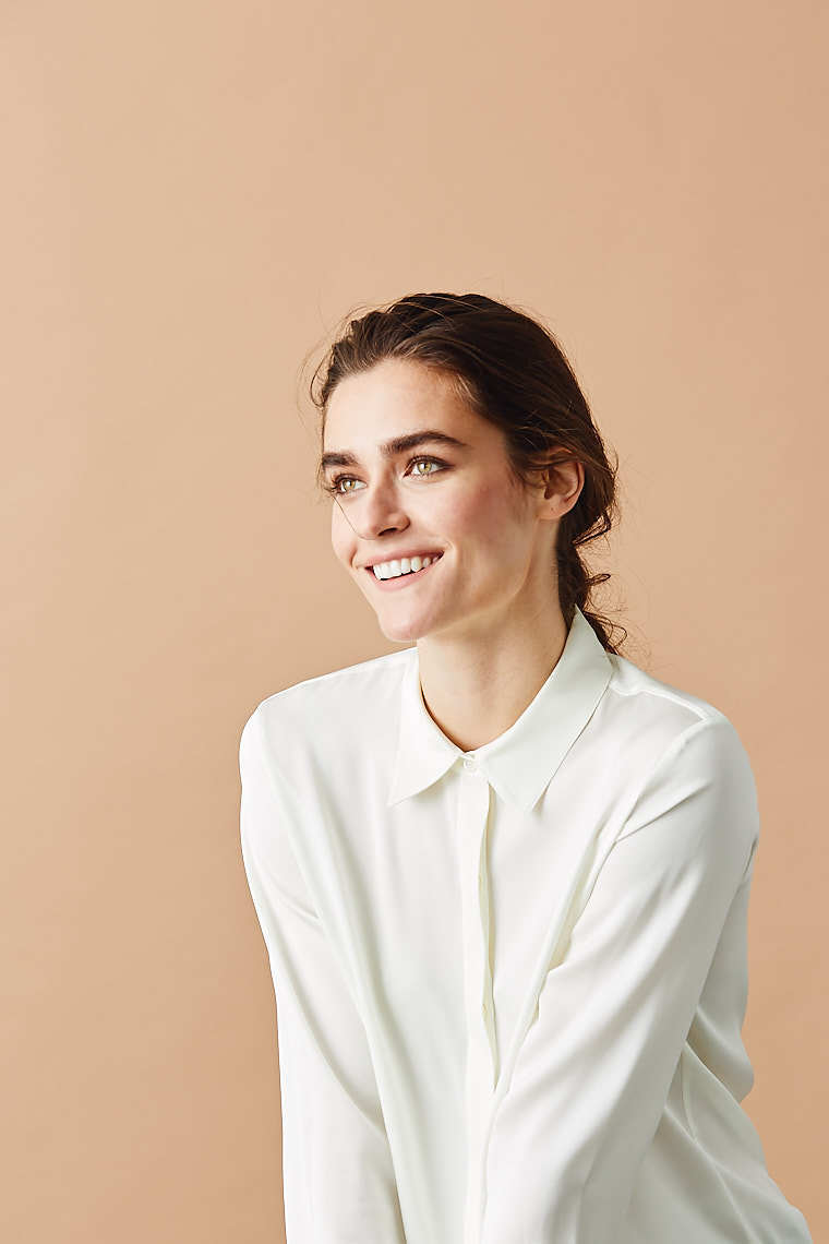 Editorial portrait of pretty female model in white collared blouse