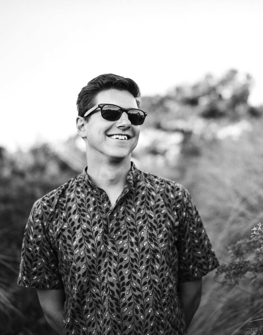 Black and white portrait of clean-shaven young man in black sunglasses