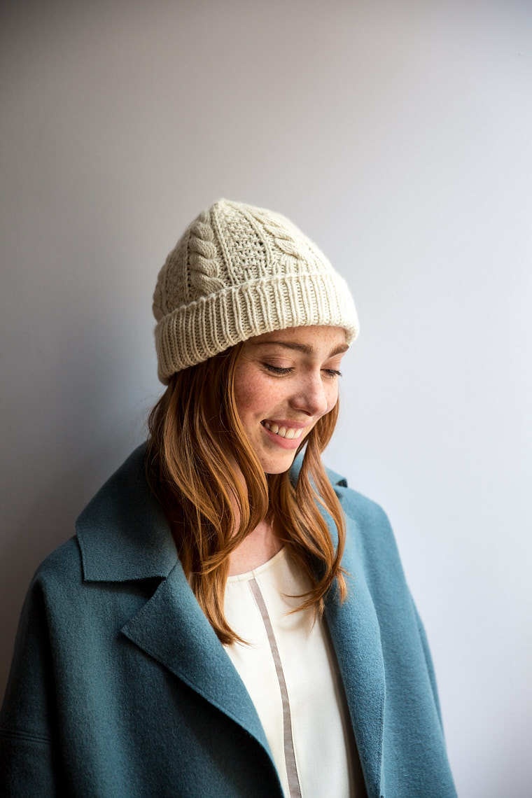Portrait of young woman smiling in white knitted hat and blue peacoat