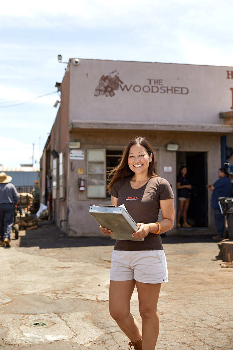 Portrait of female worker standing in front of The Woodshed with clipboard