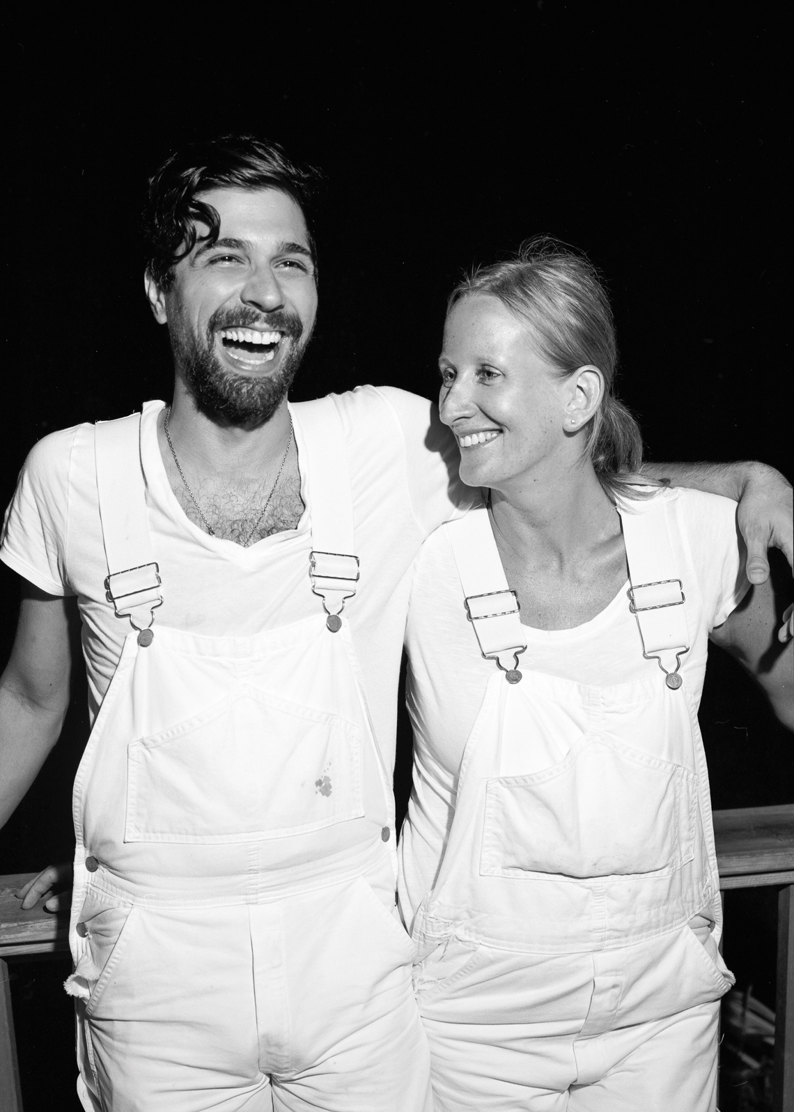 Black and white portrait of man and woman laughing in white overalls